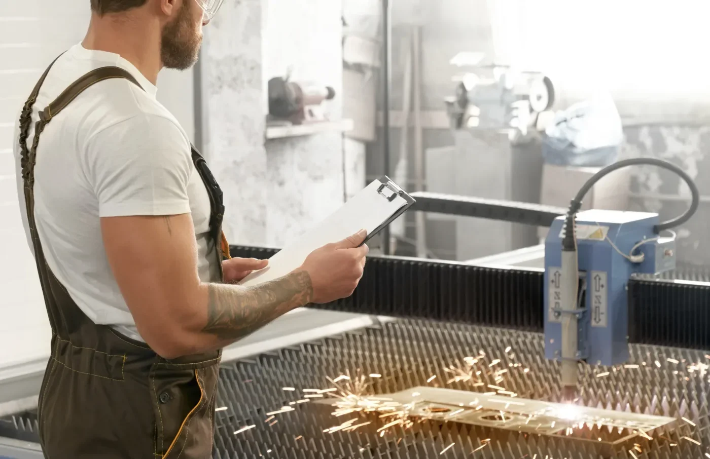 Metal işleme makinesinde üretimi kontrol eden operatör